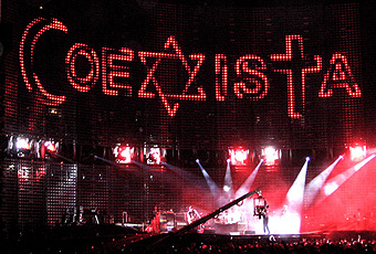 U2, 'Sunday Bloody Sunday'. 
Mexico City, ‘Vertigo’ tour, 16 februari 2006.
U2 vertoonden tijdens de show boven hun hoofden 
in grote letters het Spaanse woord 'coexista'. 
Waarbij een Halve maan de letter 'C' verving, 
een Davidster de 'X' en een Kruis de 'T'. 
Symbolen van Islam, Jodendom en christendom
staan zo samen in één woord: 'coexista': 
'naast elkaar bestaan'. 
Warko 2007 wikipedia.org
